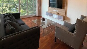A modern living room with a sofa, armchair, and a glass coffee table. - ViVi Avenue Thonglor (Bangkok)