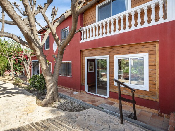 A red building with a wooden balcony, a large tree in front, and a stone pathway. - D'estiu by Interhome (Burriana)