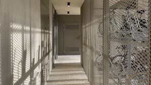 A corridor with a mesh wall on one side and a plain wall on the other, leading to a door at the end. - Immediate proximity to the Bordeaux hyper center (Bruges)