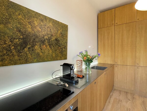 A modern kitchen with a built-in oven, a coffee machine, and a vase with flowers on the counter. - Immediate proximity to the Bordeaux hyper center (Bruges)
