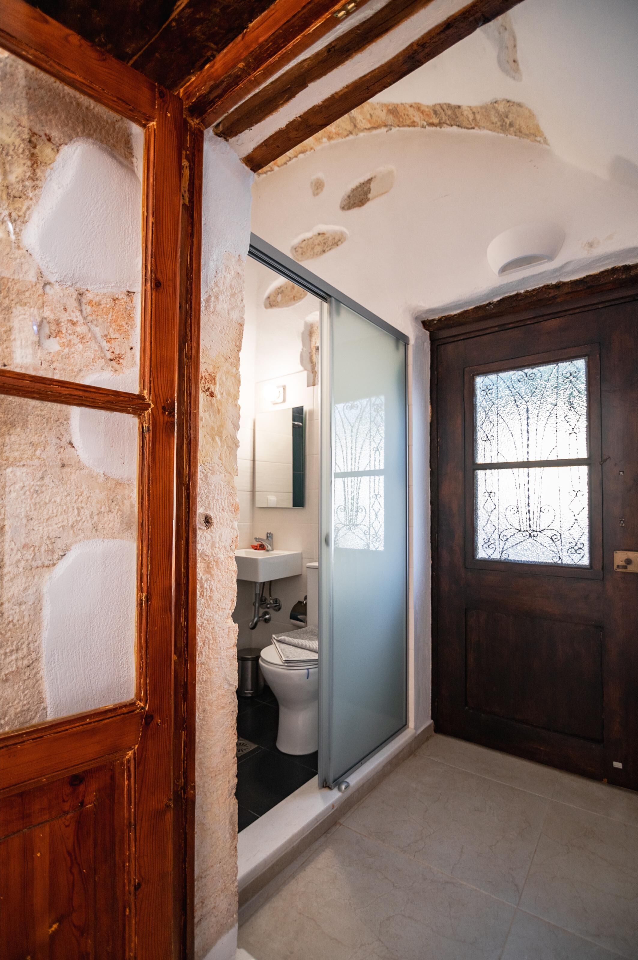 A narrow hallway with a wooden door and a window with decorative glass.