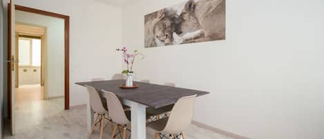 Un coin repas comprenant une table, des chaises, un vase avec des fleurs et un tableau accroché au mur.