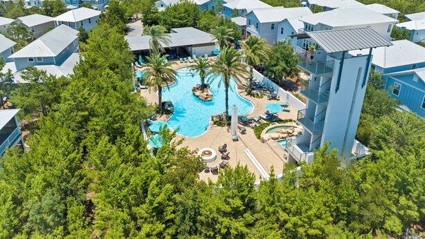 A resort with a central swimming pool surrounded by palm trees and lounge chairs.