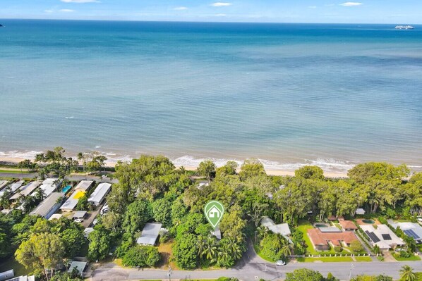 Vue aérienne d’une propriété côtière comprenant plusieurs bâtiments, une plage et une végétation luxuriante.