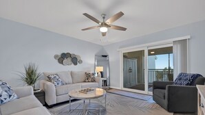 Ein modernes Wohnzimmer mit Deckenventilator, einer Sofagarnitur, einem Couchtisch und einem gemusterten Teppich.