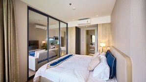A hotel room with a large bed, a desk, a chair, a mirror, and a sliding door leading to a bathroom. - Once condo - Pattaya central location  (Pattaya)