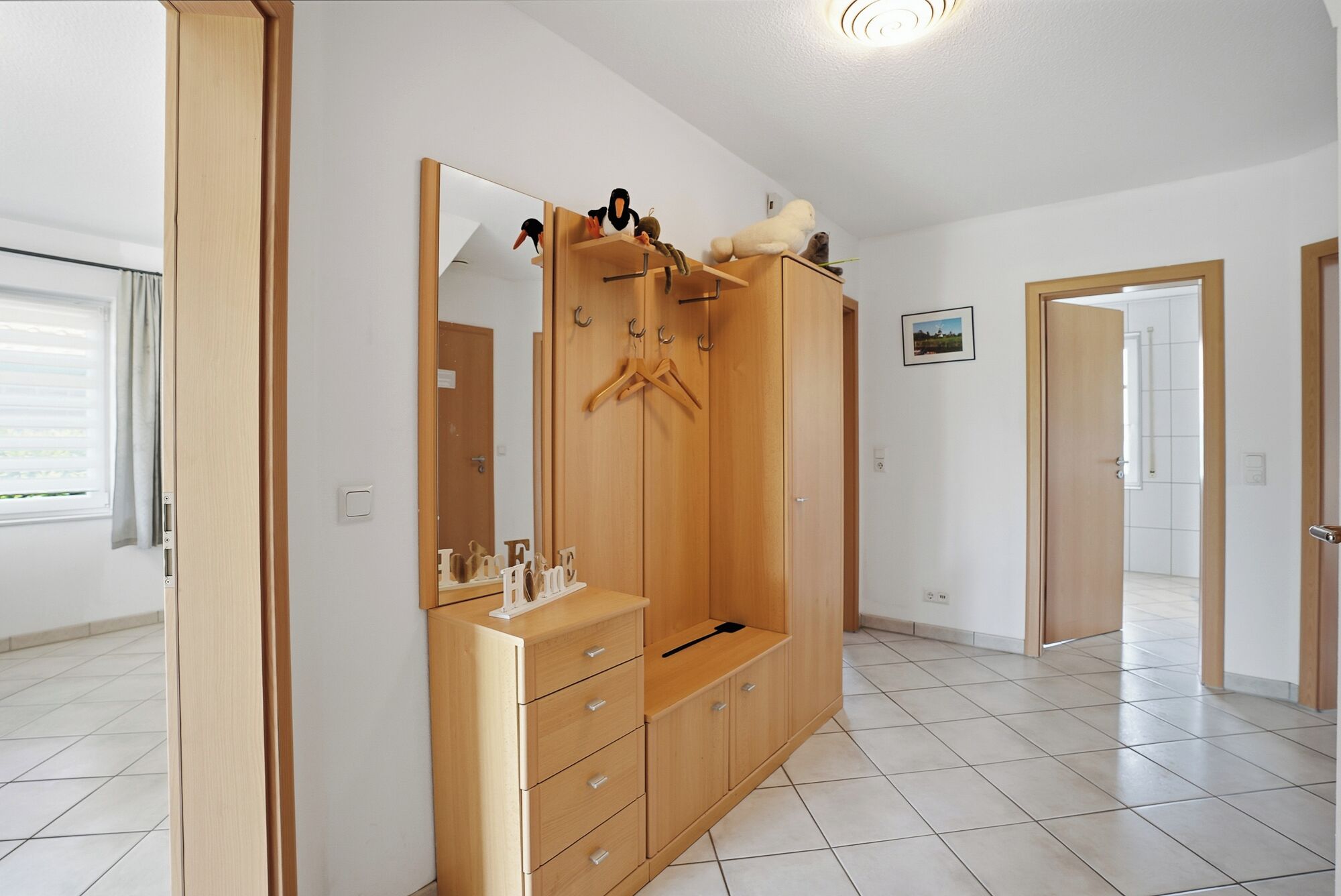 Una habitación con un armario de madera, un espejo y una puerta que da a otra estancia.