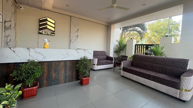 A reception area with a marble counter, two sofas, and potted plants.