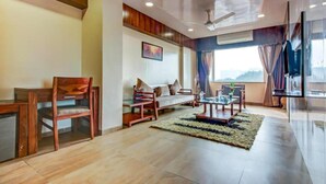 A modern living room with a sofa, chairs, a coffee table, and a TV. - Hotel Shree Daan (Vapi)
