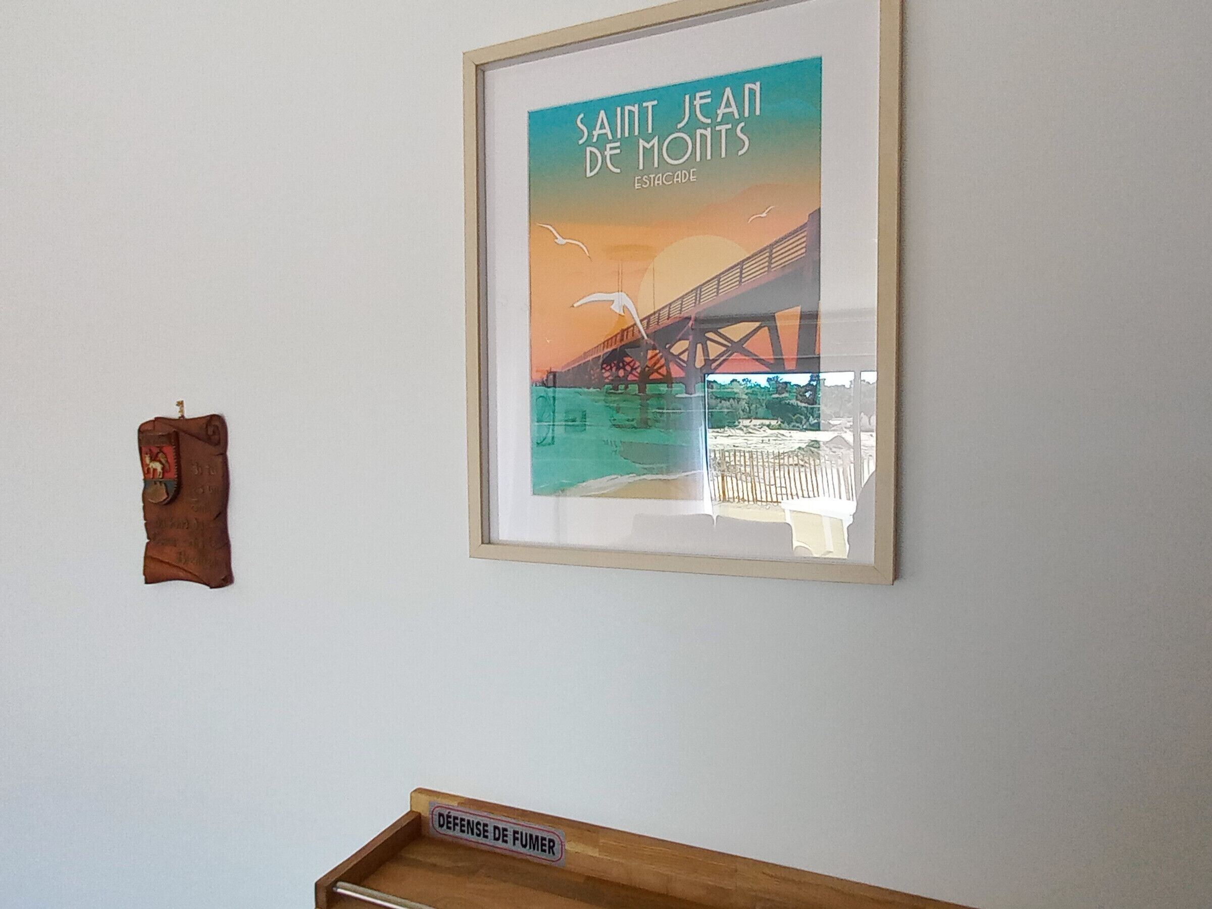 Um quadro de uma ponte com o texto "SAINT JEAN DE MONTS ESTACADE" numa parede branca.