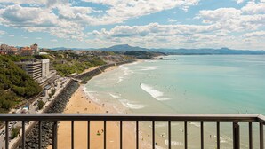 Une vue côtière avec une plage, une côte rocheuse et des bâtiments en arrière-plan.