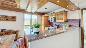 Une cuisine avec des poutres en bois, un plan de travail en granit et une vue sur l’extérieur.
