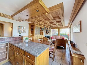 A spacious kitchen with a large island, wooden cabinets, and a stone fireplace.