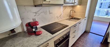 Una cocina compacta con microondas integrado, un fregadero y una estufa horno.