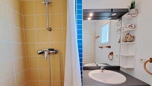 A bathroom with yellow tiles, a shower, a sink, and a mirror. - "Charming 2-Room Apartment with Direct Beach Access and Sunny Terrace" (Marseillan-Plage)