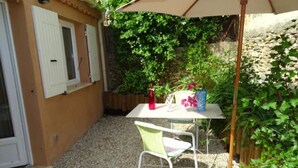 A small patio area with a table and chairs, a bottle, and a vase with flowers.