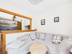 A modern living room with a large sofa, a round wooden coffee table, a mirror, and two framed pictures on the wall. - Bright apartment with terrace, parking, and WIFI in Les Gets (Les Gets)