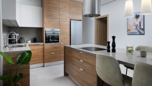 Une cuisine moderne dotée de meubles en bois, d’appareils électroménagers en acier inoxydable et d’un coin repas avec une table et des chaises.