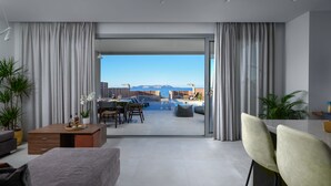 Un salon moderne avec vue sur la mer, un coin repas et un balcon doté d’un espace salon extérieur.