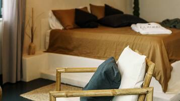 Un dormitorio con una cama, dos lámparas colgantes, una silla de madera y un ventanal con cortinas.