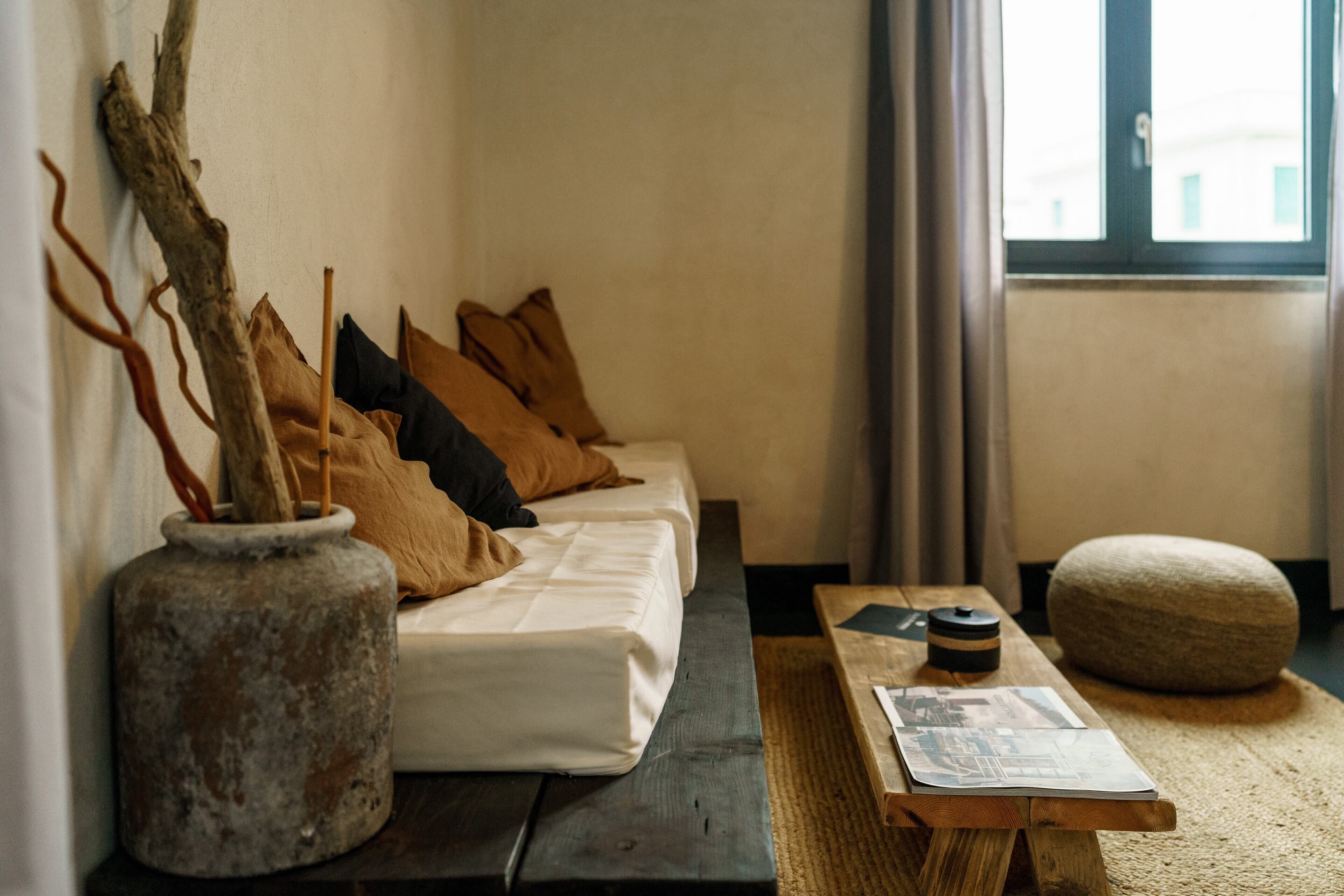 Una habitación acogedora con un sofá, una mesa de madera y un pouf de piedra.