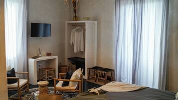 Un dormitorio moderno con cama, televisión montada en la pared, armario y pequeño escritorio con silla.