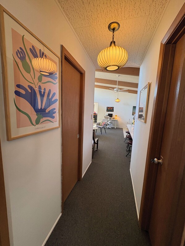 A hallway with a ceiling fan, a hanging light fixture, and a framed artwork on the wall. - Skyway Retreat: Luxury 1000 sq. ft. Secluded Mid-Century Guesthouse (Colorado Springs)