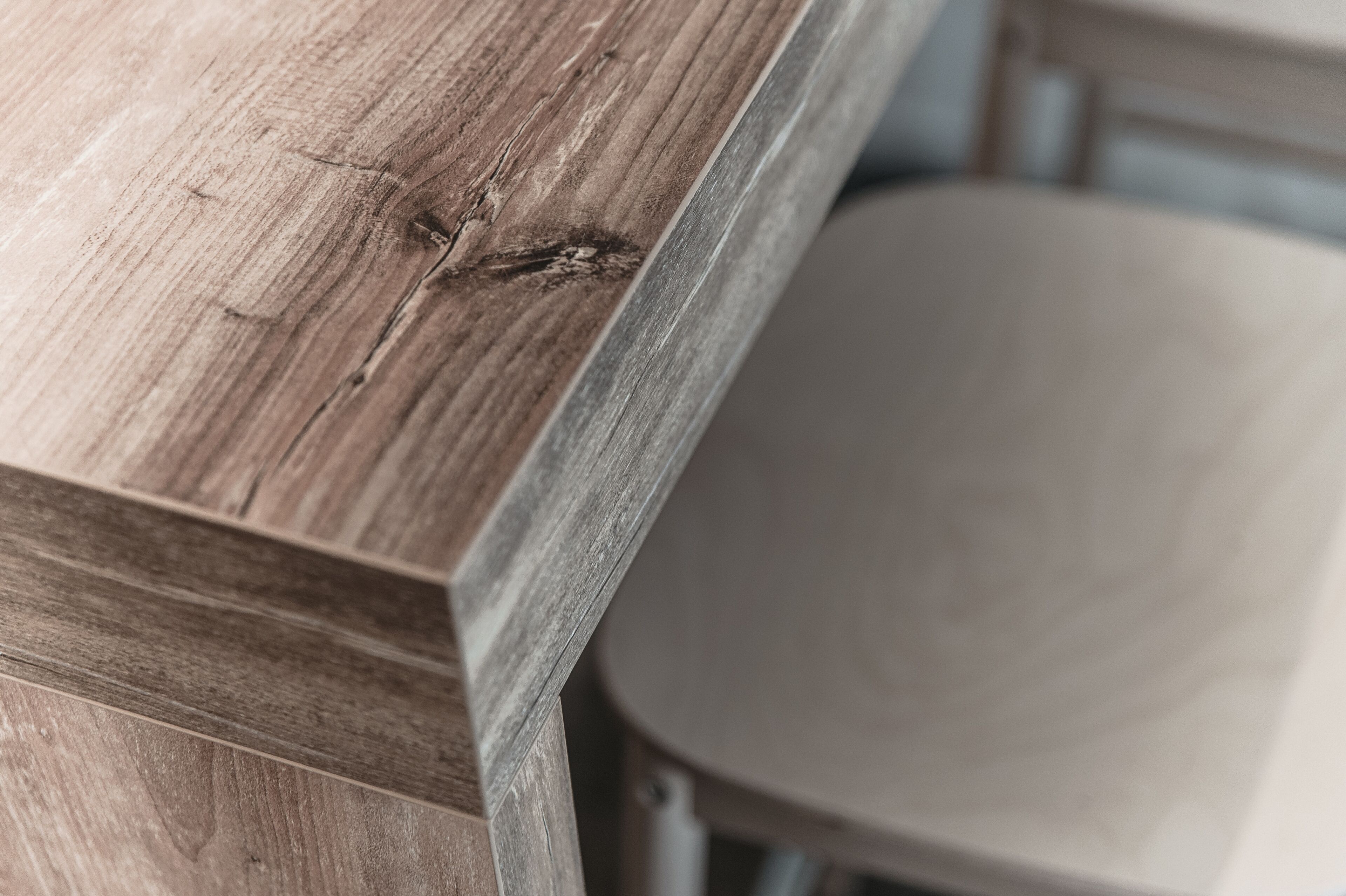 Un gros plan d’une surface en bois, où l’on distingue le veinage et une petite éraflure.