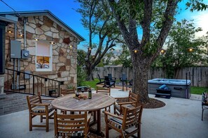 Une maison en pierre dotée d’un patio, d’un espace salon extérieur et d’un jacuzzi.