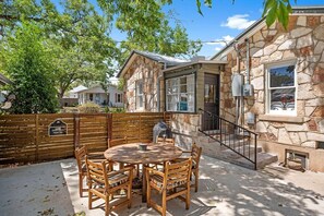 Une maison en pierre avec un patio, une table ronde en bois et des chaises.