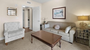A living room with a beige sofa, a patterned armchair, a wooden coffee table, a framed picture on the wall, and a lamp on a side table. - Relax and Unwind: Oceanfront 1 Bdrm Condo (North Myrtle Beach)