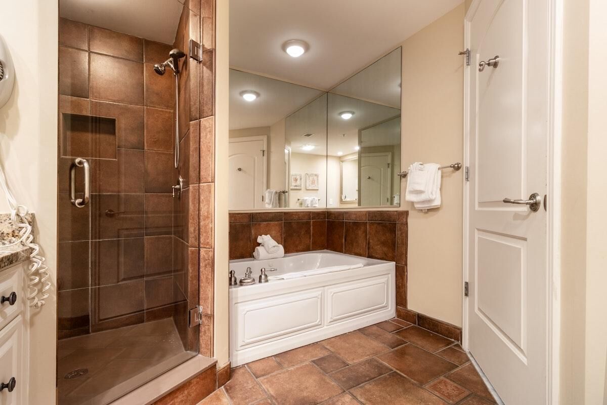Une salle de bain avec une douche à l’italienne, une grande baignoire et un miroir au-dessus du lavabo.