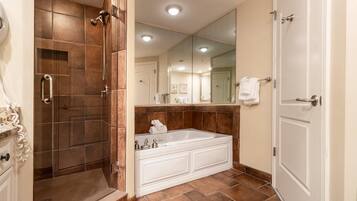 Une salle de bain avec une douche à l’italienne, une grande baignoire et un miroir au-dessus du lavabo.