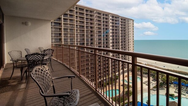 A balcony with outdoor furniture, overlooking a pool and beach area. - Beachfront Beauty 2BR 2BA Condo with Kitchen (North Myrtle Beach)