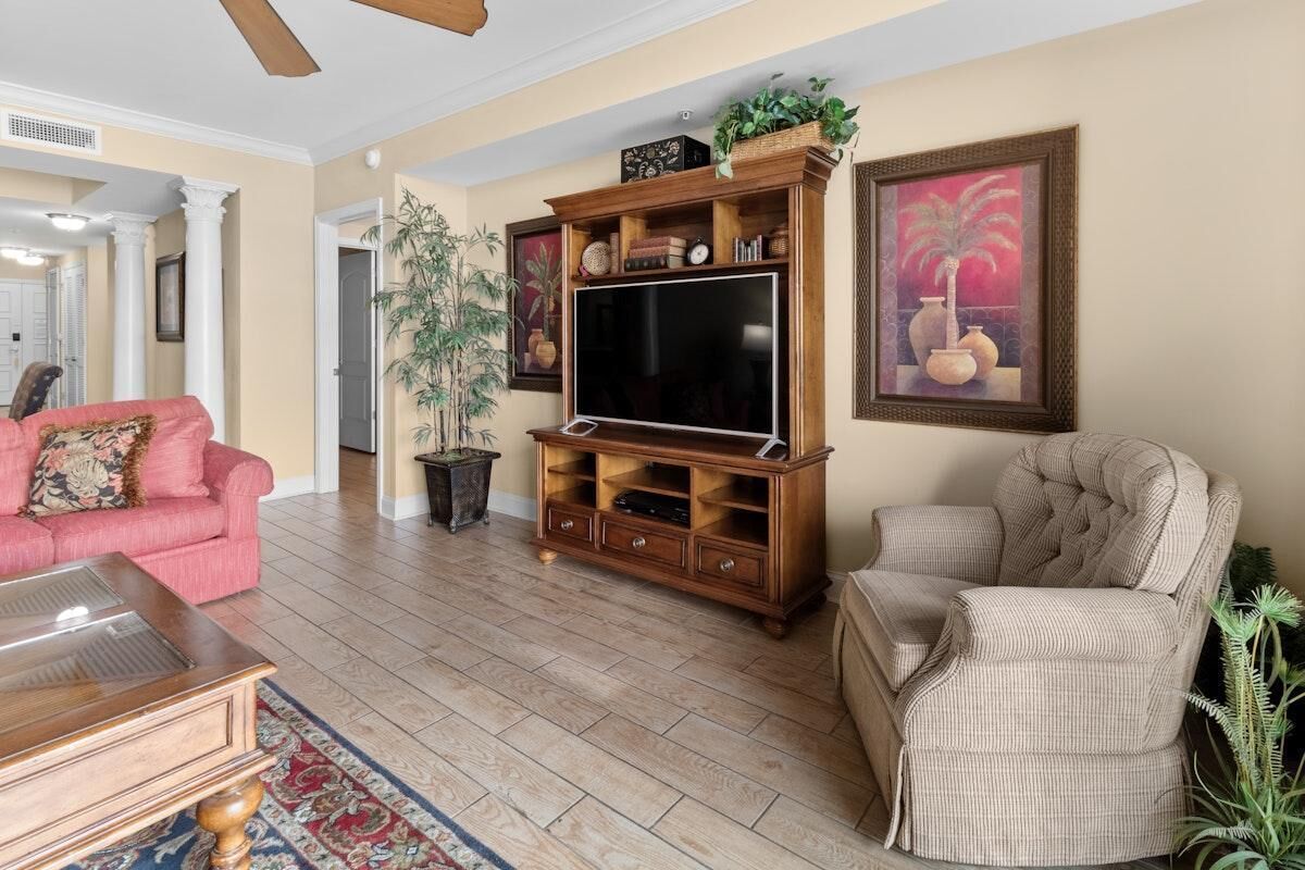 A living room with a wooden entertainment center, a pink sofa, a beige armchair, and a large TV.
