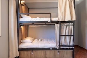 Un lit superposé avec une couchette inférieure en bois et une couchette supérieure noire.