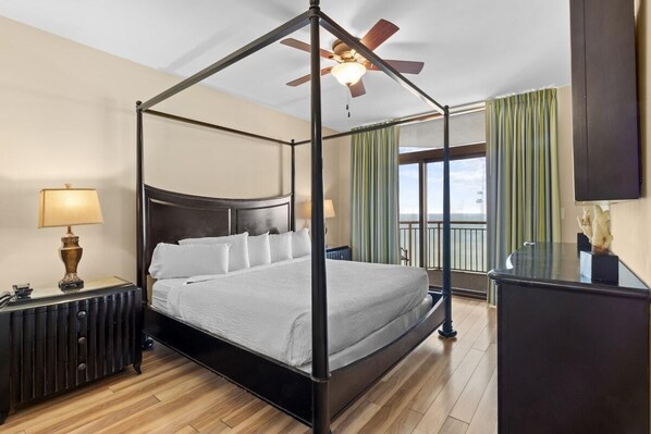 A four-poster bed with a ceiling fan, a nightstand with a lamp, and a dresser. - Beachfront Beauty Breeze 2BR Condo (North Myrtle Beach)