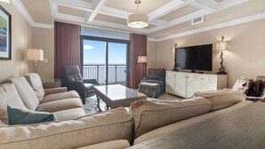 A spacious living room with a large sofa, a coffee table, a TV, and a balcony with a view. - Unparalleled Luxury: 3 Bdrm Condo with Whirlpool (North Myrtle Beach)