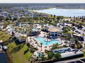 Resort com várias piscinas, um edifício central e uma grande extensão de água ao fundo.