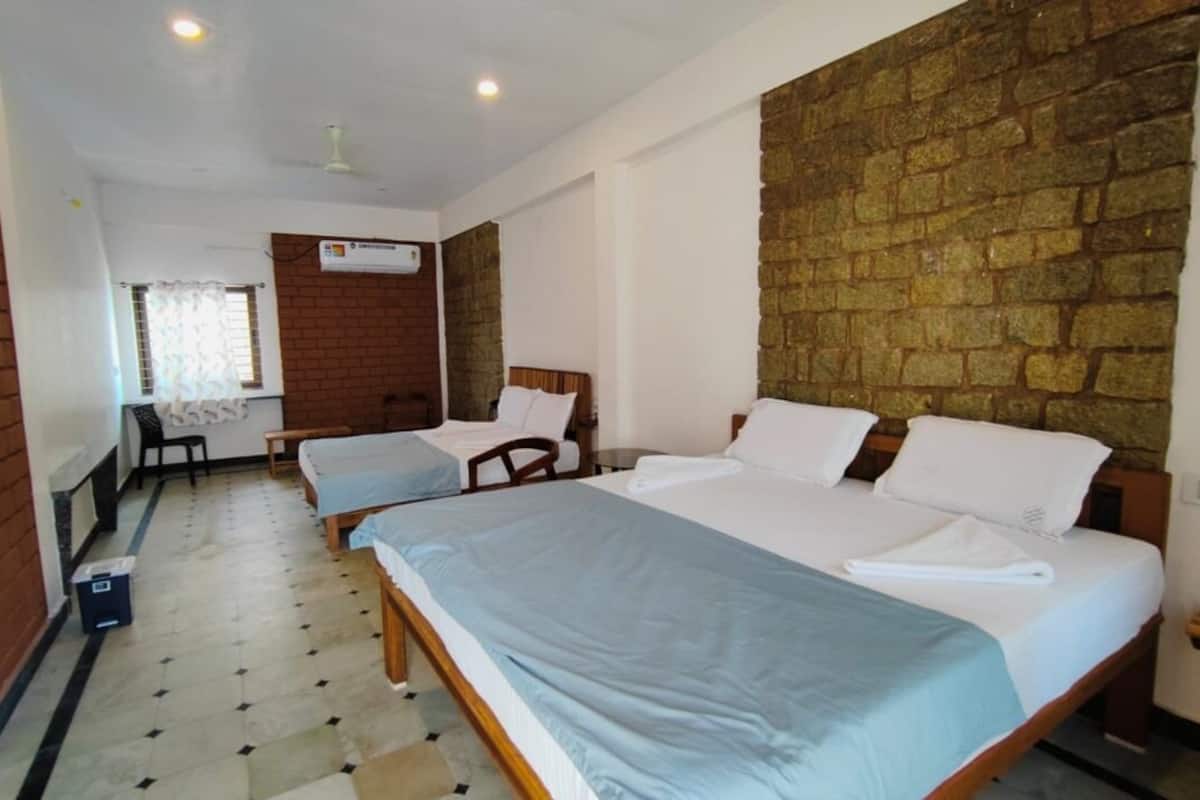 Une chambre d’hôtel avec deux lits, un mur en briques, un mur en pierre et un sol carrelé.