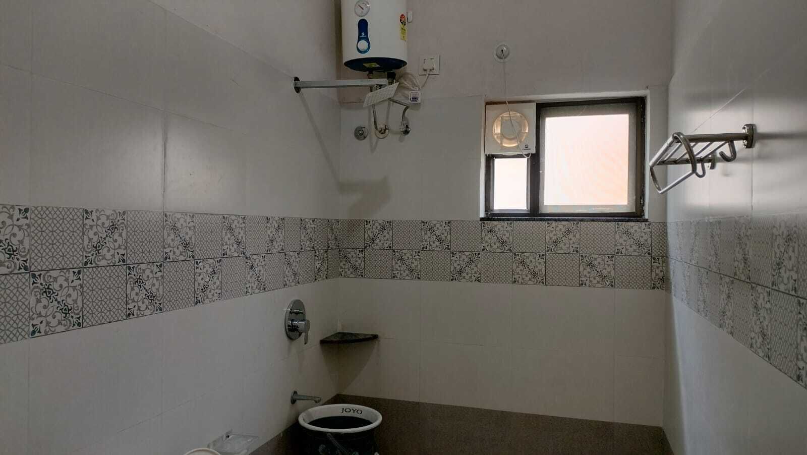 A bathroom with a toilet, a window, and a wall-mounted air conditioning unit.