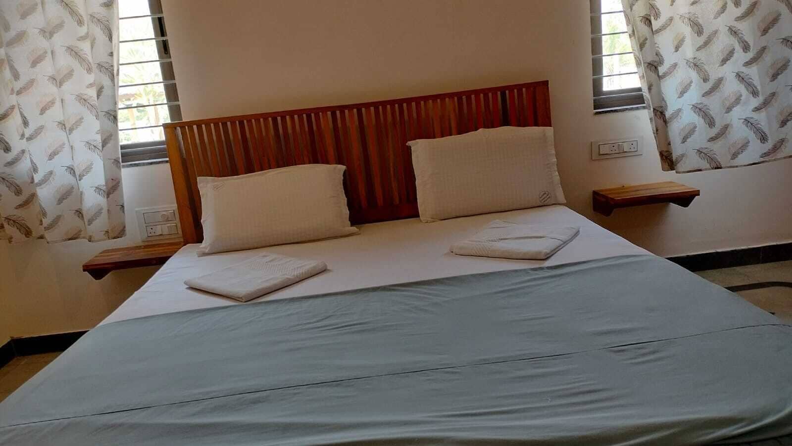 Una cama bien hecha con cabecera de madera, dos almohadas y una colcha doblada.