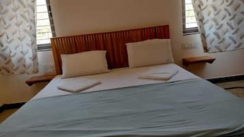 Una cama bien hecha con cabecera de madera, dos almohadas y una colcha doblada.