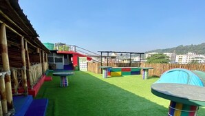 A playground with artificial grass, colorful play structures, and a wooden fence. - Tridhara Homestay (Guwahati)