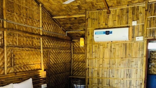 A room with a bed, a ceiling fan, and a wall-mounted air conditioning unit. - Tridhara Homestay (Guwahati)