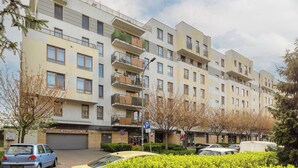 A multi-story residential building with balconies, a parking sign, and a clear sky. - Elegant Apartment in Wola | Terrace from Two Rooms (Warszawa)