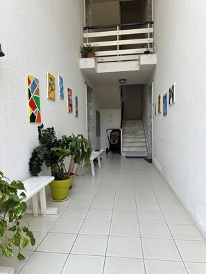 Relax in a peaceful space with a bench, table, and potted plants, surrounded by framed artworks and a staircase.