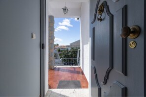 A door leading to a balcony with a view of buildings and a clear sky.