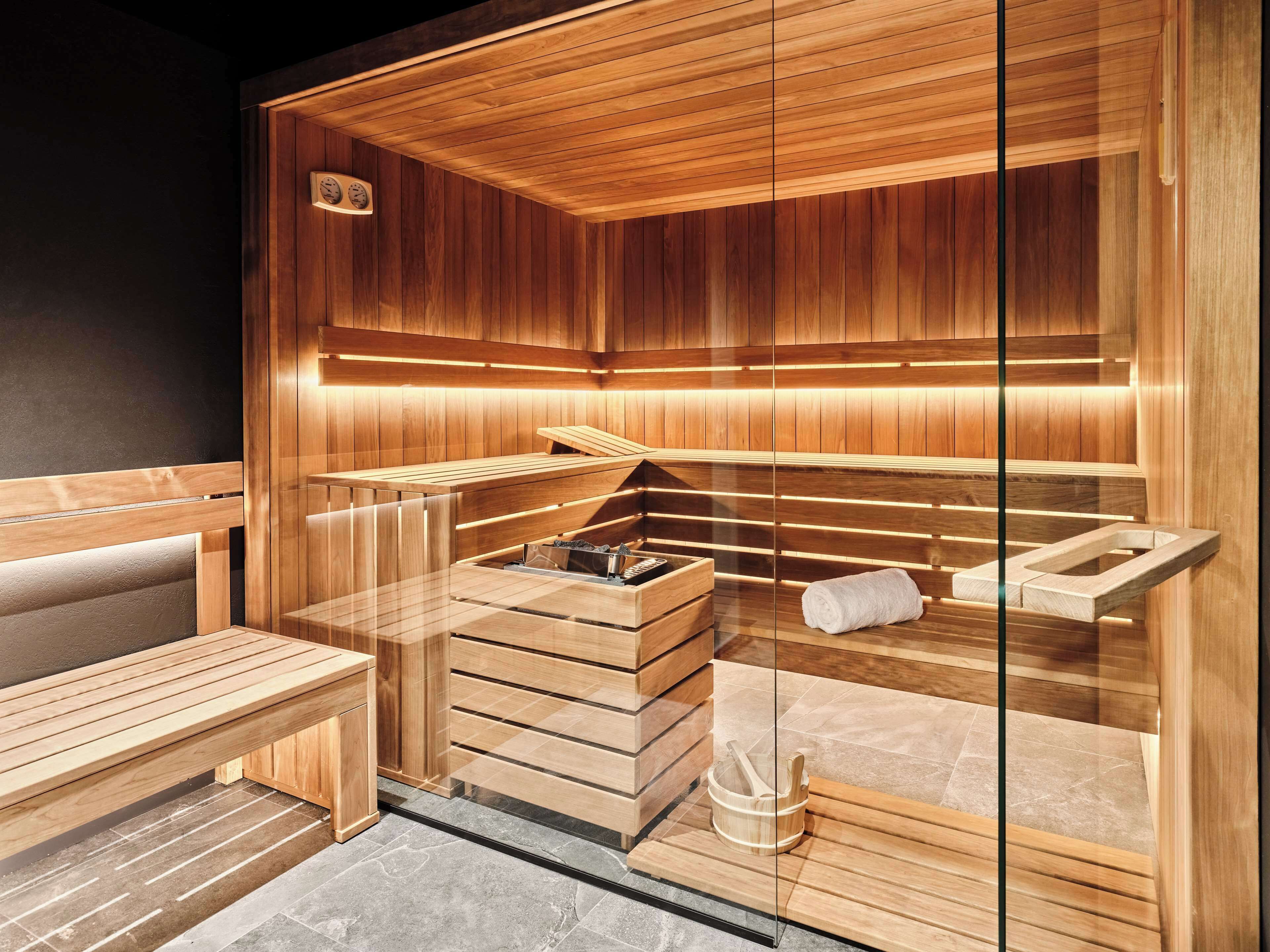 Un sauna avec des bancs en bois et un banc muni d’une serviette.