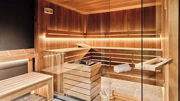 Un sauna avec des bancs en bois et un banc muni d’une serviette.